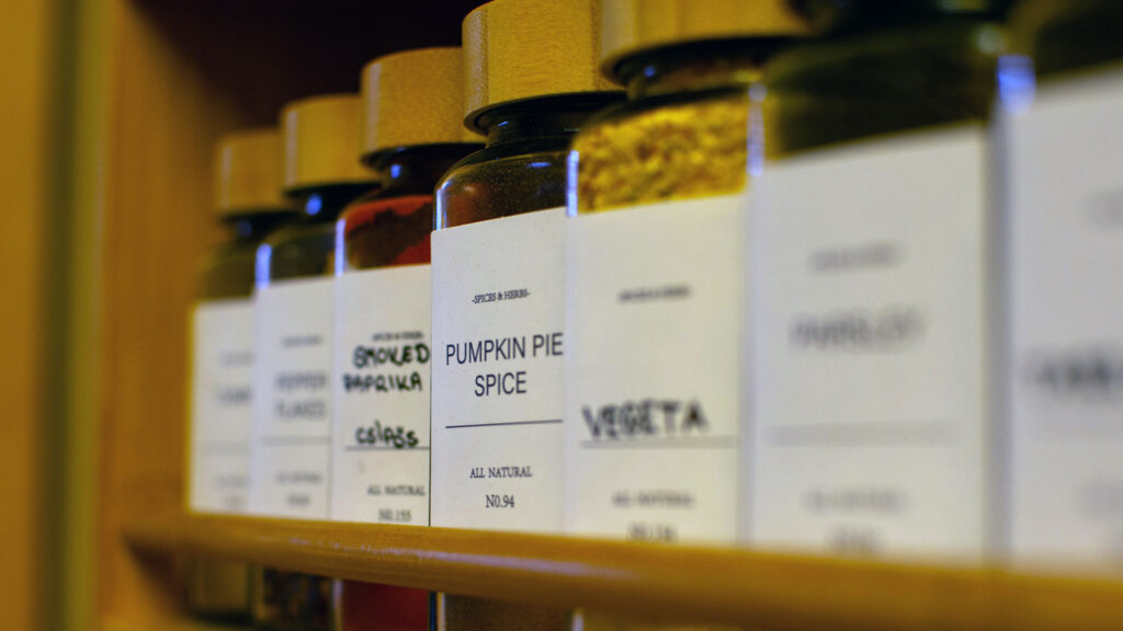 Row of spice rack bottles with pumpkin pie spice in focus