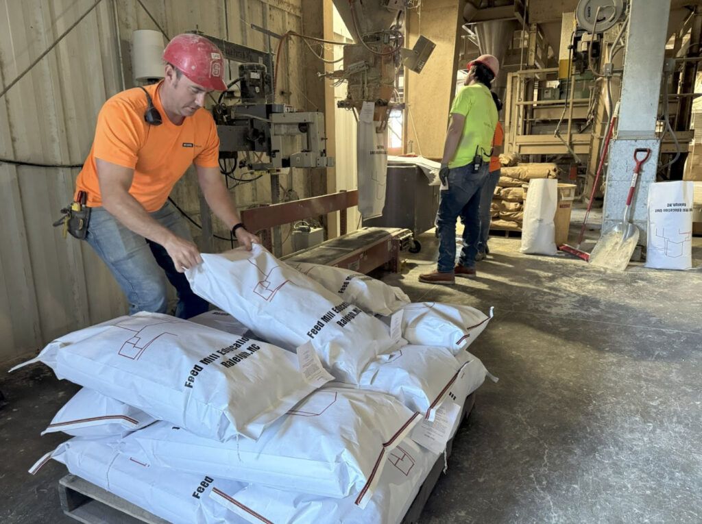 a man grabs a feed bag from a pallet