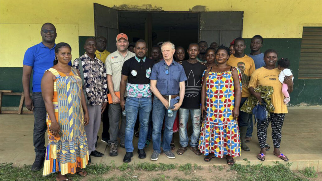 a group of people stand outside a yellow building in Ivory Coast Africa