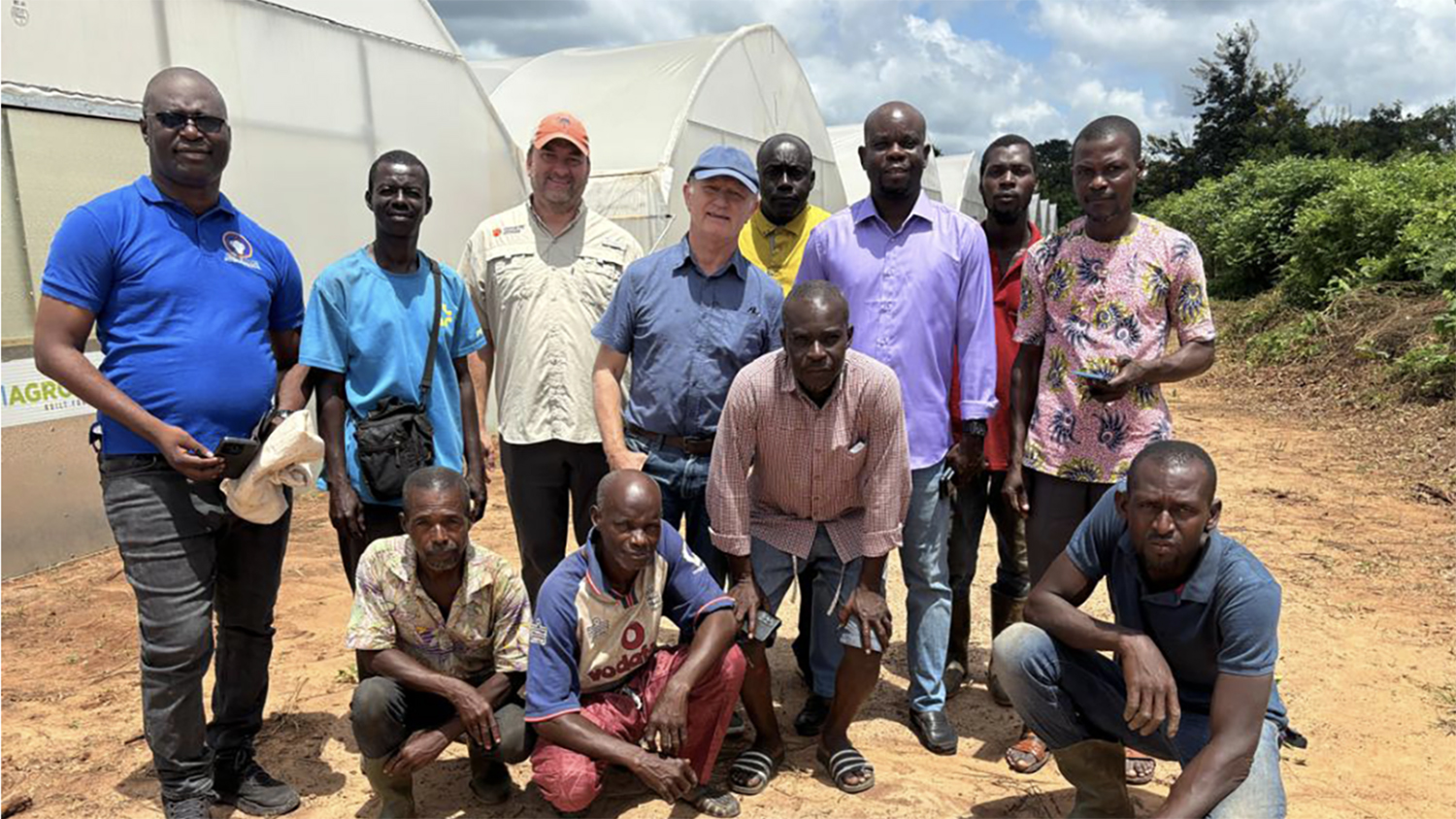 a group of people stand outside greenhouses in Ivory Coast