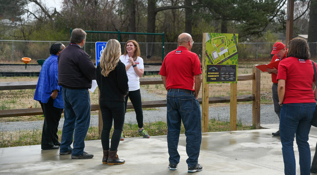 a woman speaks to a group of people outdoors