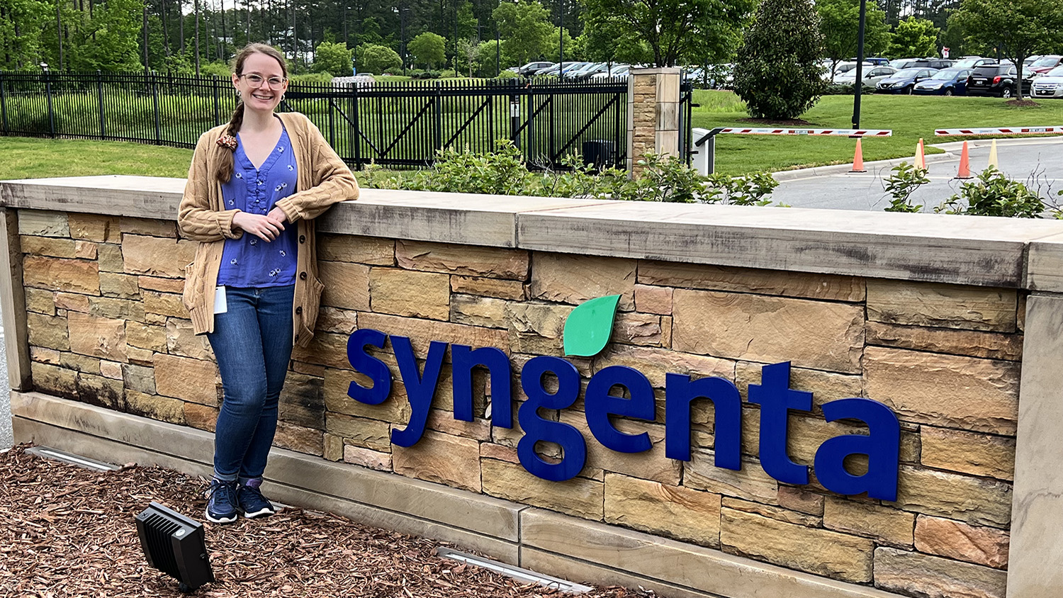 a women stands outside next to a sign that says syngenta