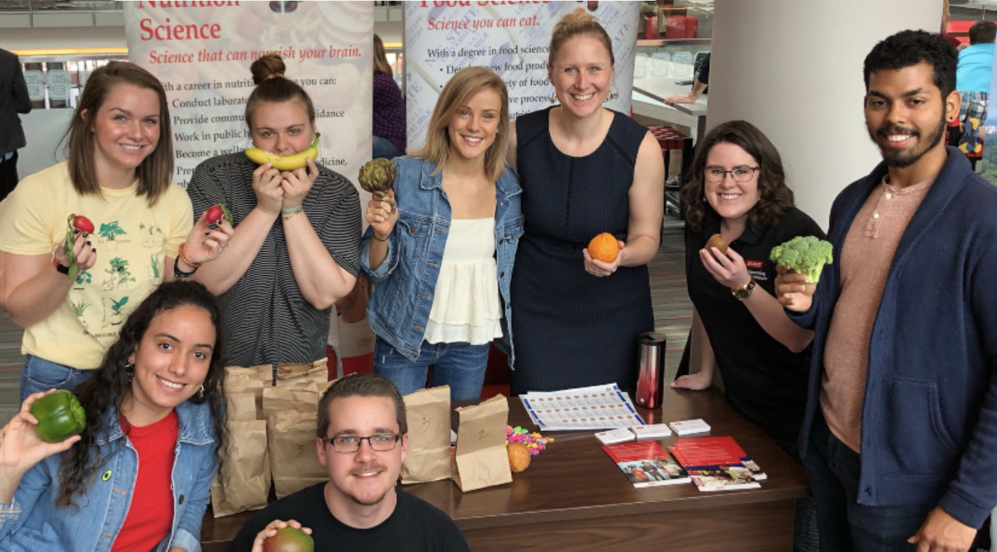 a group of people holding fruits and healthy foods