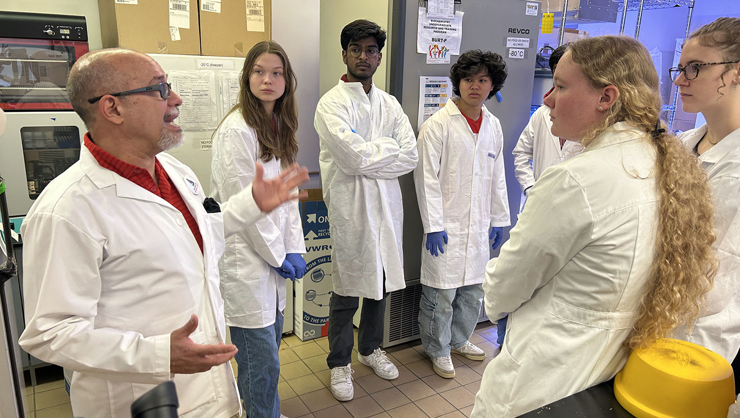 a group of people stand talking in a science lab