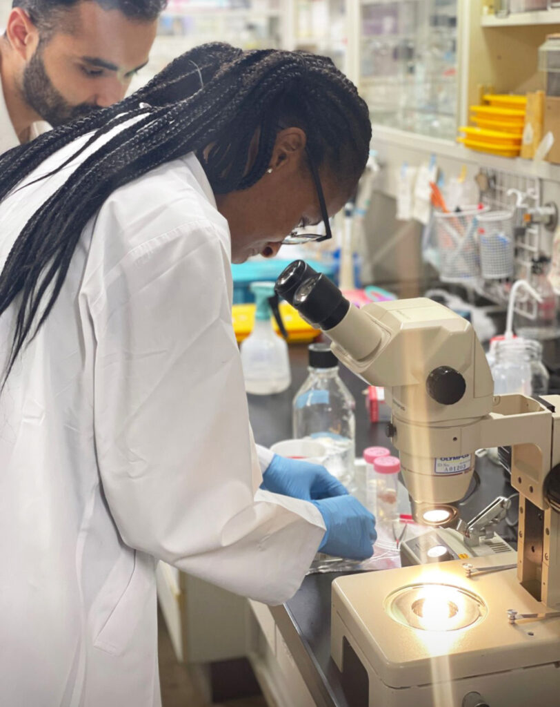 Man and woman in lab coats using microscope