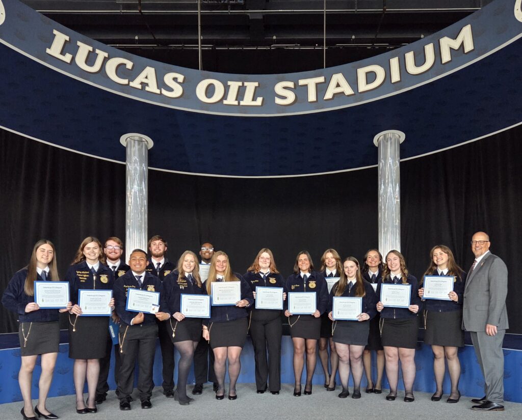 A group of students on a stage holding certificates