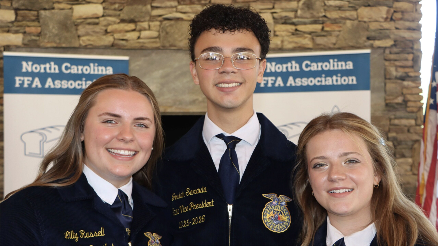 a young woman, a young man and a young woman stand together wearing velvet navy blue FFA jackets