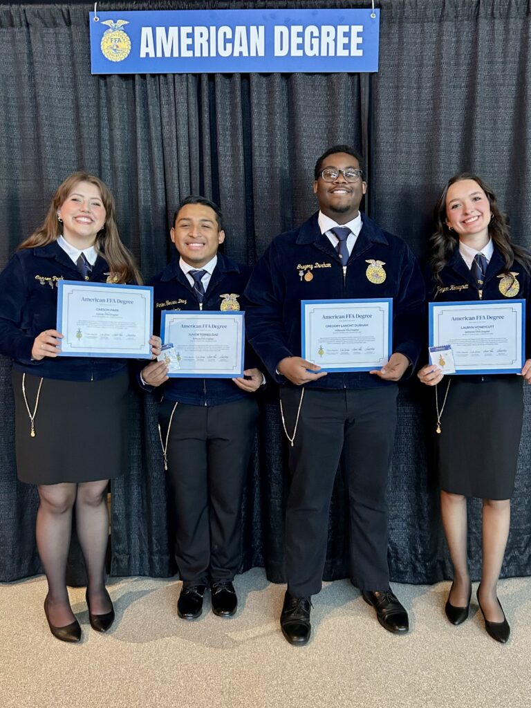 A group of students in front of a gray curtain holding certificates