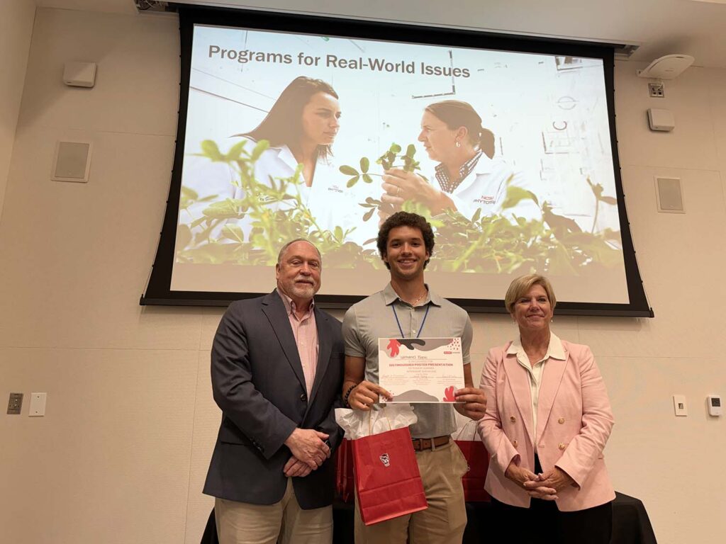 a young man holding a certificate stands between a man and a woman
