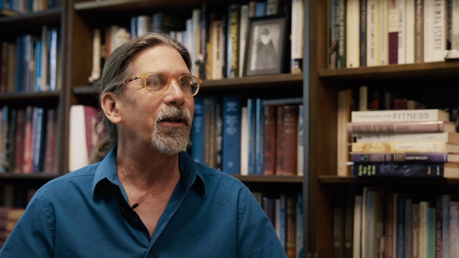 William Kimler in front of a bookshelf