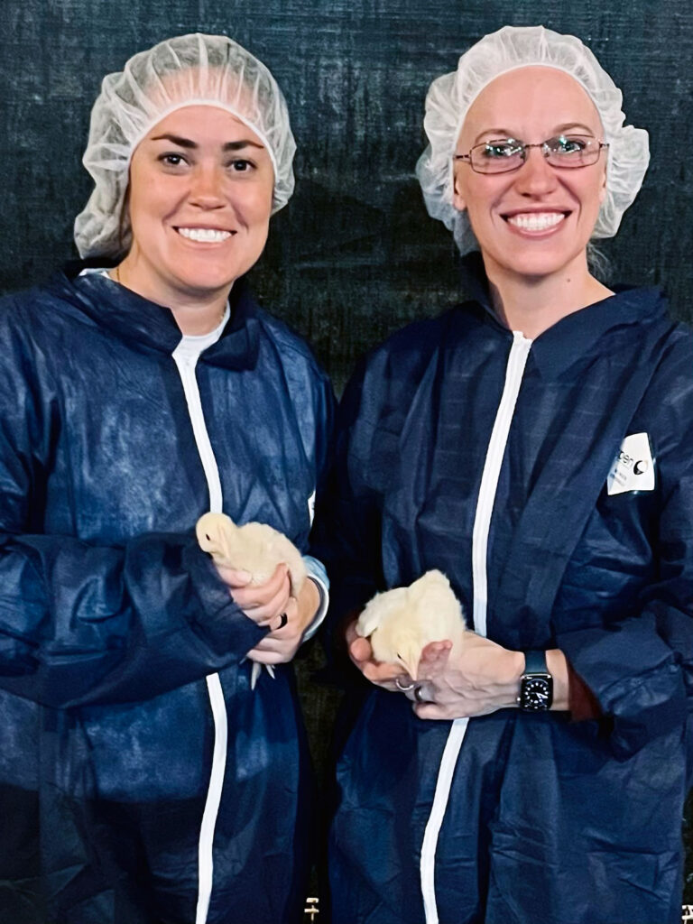 Tori Rumenik, executive director of the NC Ag Partnership, and Summer Lanier hold chicks while wearing caps and personal protective equipment on a tour of Butterball's Mt. Olive processing plant.