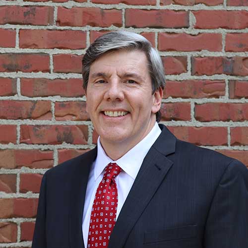 a man with gray hair in front of a red brick building