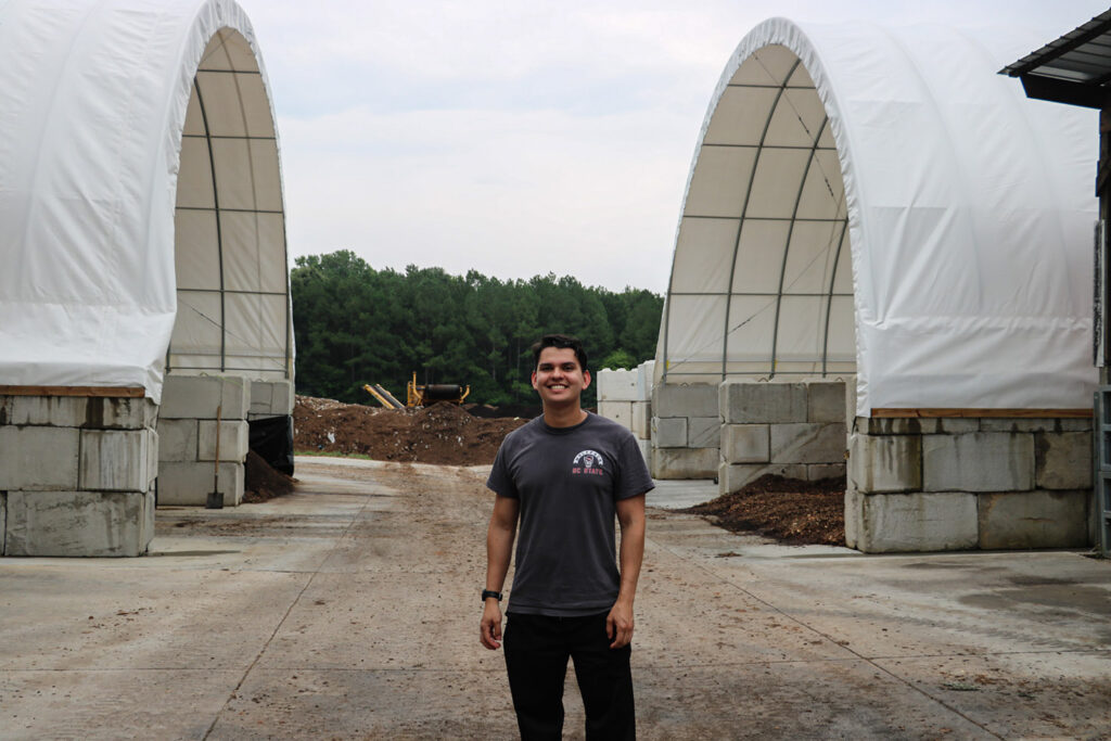 a man stands between two covered sections of compost