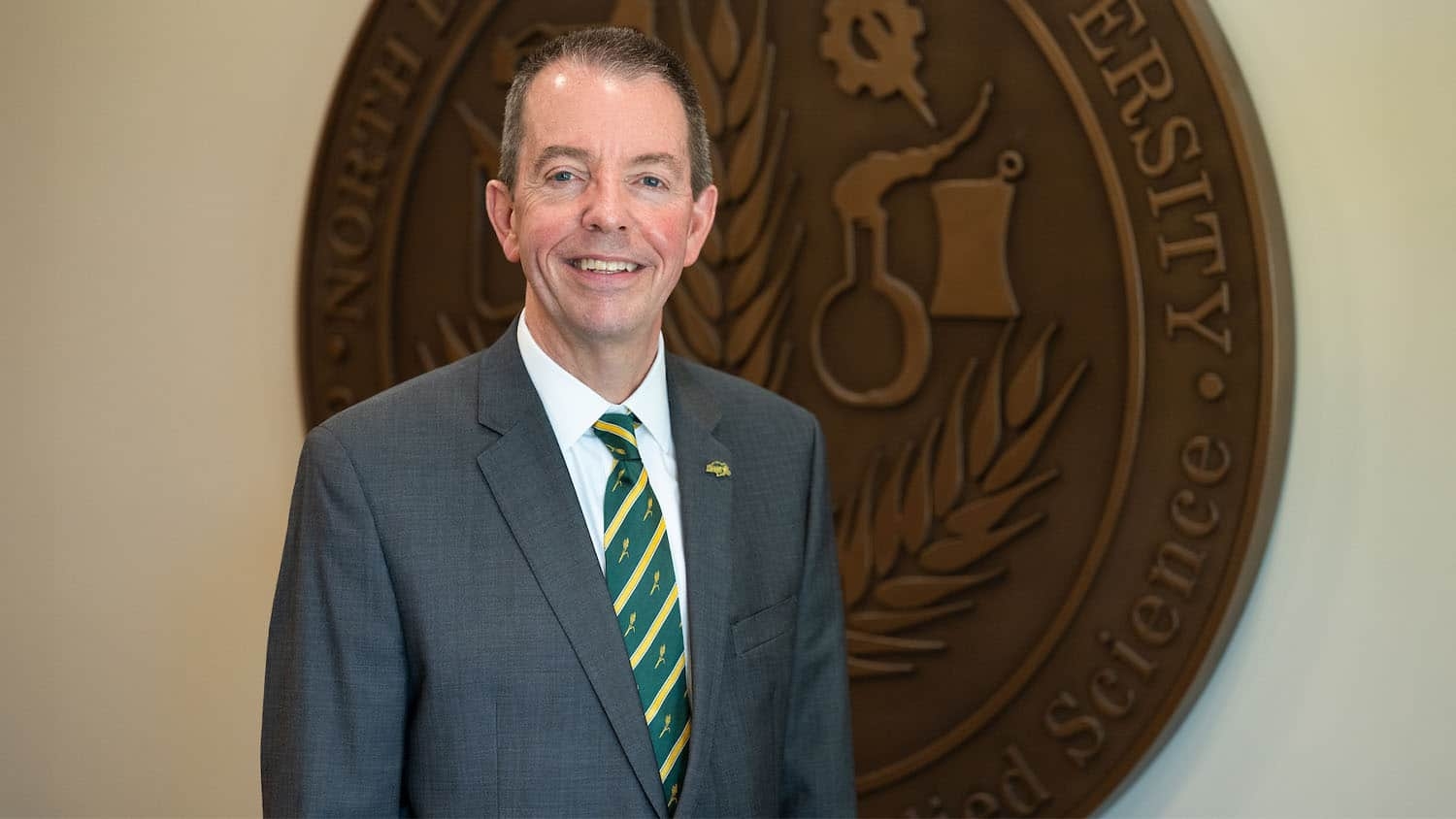 Marshall Stewart in front of the North Dakota State University seal.