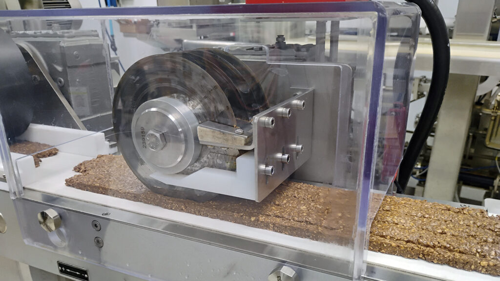 industrial food processing equipment moving a tray of brown bars along the production line