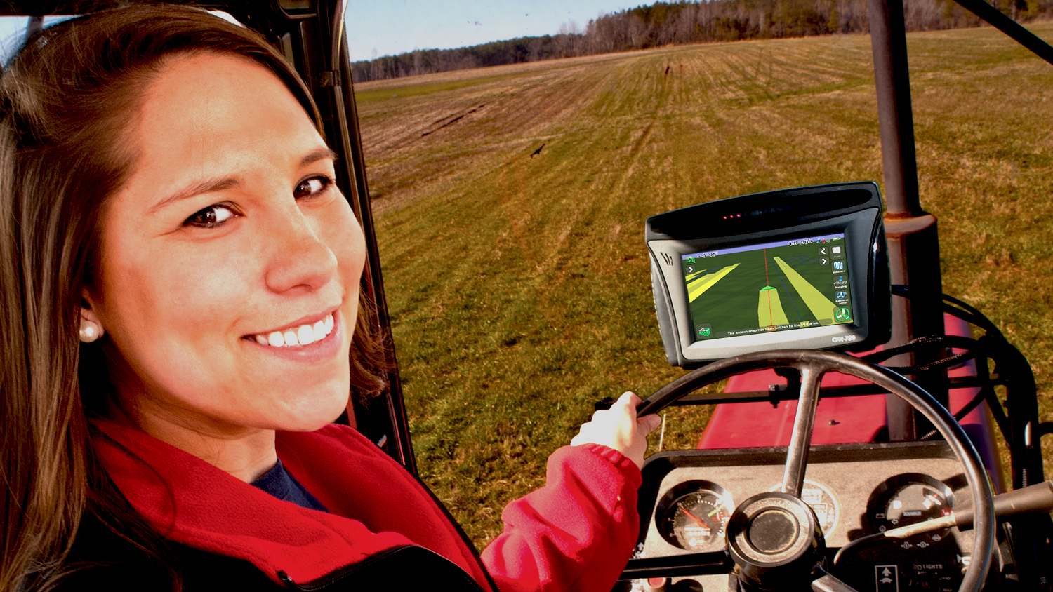 Female farmer driving a tractor in a field.