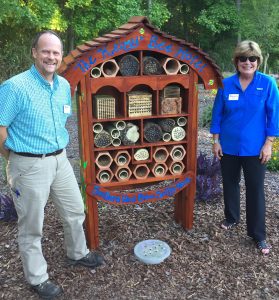 In the Choice Plants garden, Marshall Warren and Jody Boronkay standing at a wooden structure known as the bee hotel.