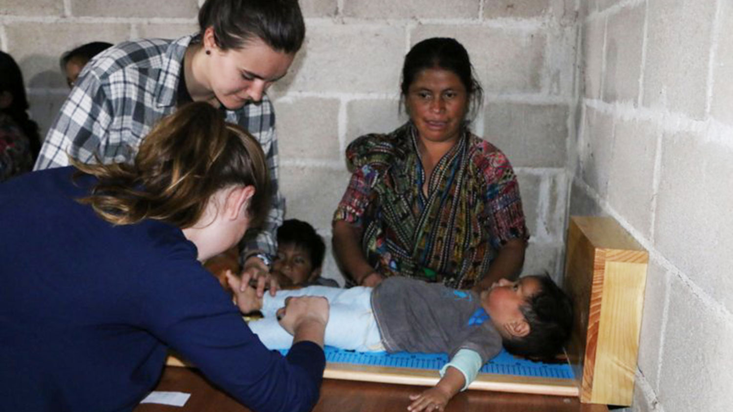 CALS student Kati Scruggs assisting with a child's medical exam in Guatemala