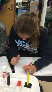Student writes in her notebook at her desk.