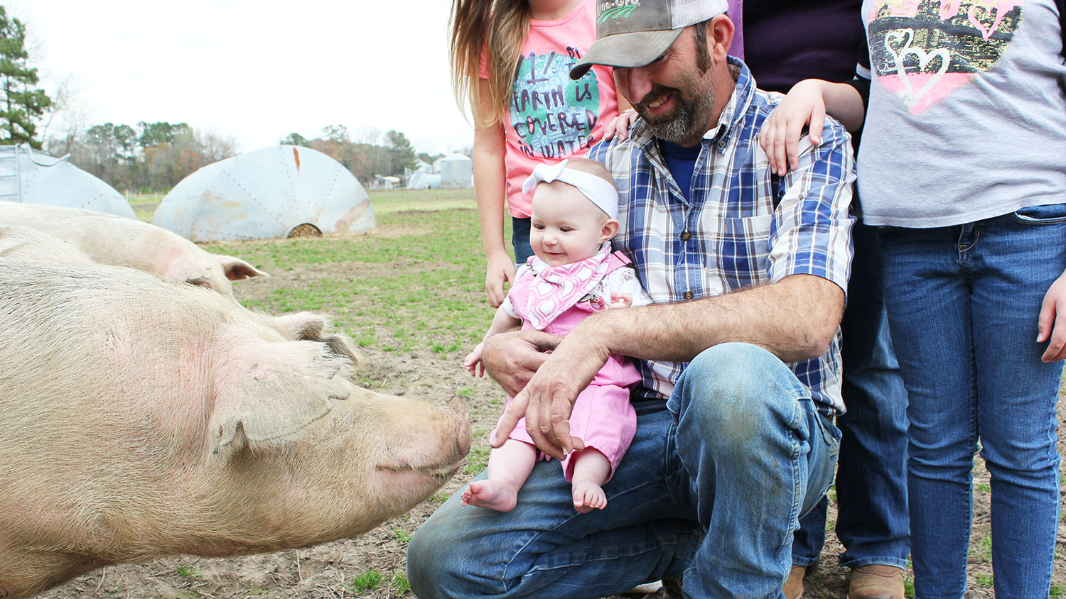 man holding baby with pig