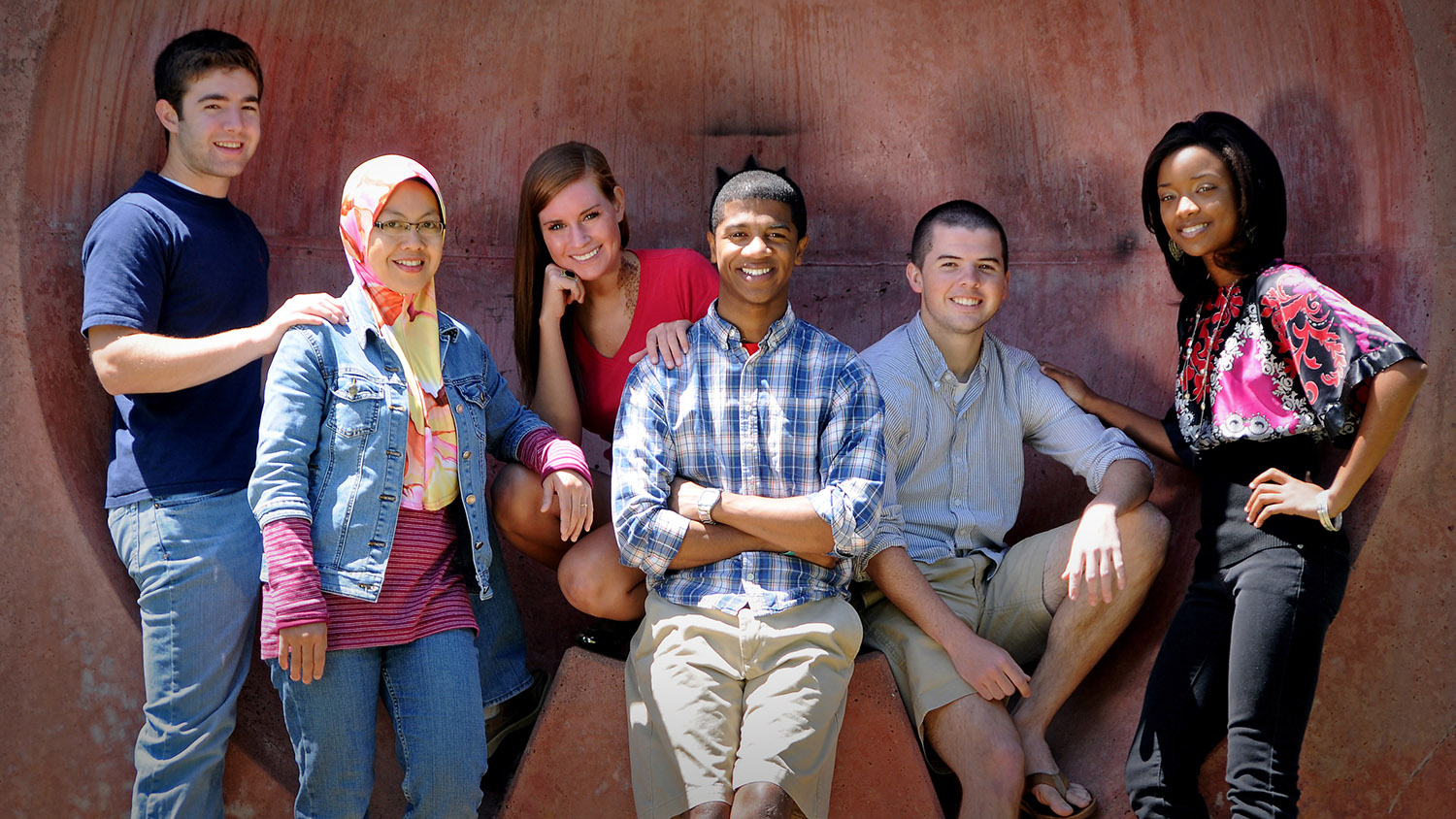 Three female students and three male students pose in the wolf ears in the brickyard.