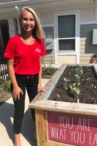 Young woman standing next to a plant bed