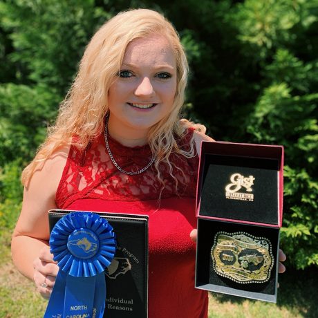 4-H'er holds the blue ribbon and buckle she won in the state contest.